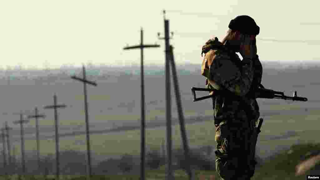 A Ukrainian soldier stands guard outside a Ukrainian Army military camp set up on a field close to the Russian border in east Ukraine. (Reuters/Yannis Behrakis)