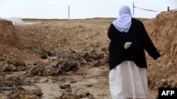 A Yazidi woman searches for clues in February 2015 as to the whereabouts of missing relatives among remains at a mass grave of victims of Islamic State (IS) militants in Iraq's Sinjar region.