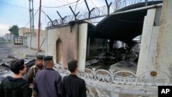 Security force and civilians gather near the burned Iranian consulate in Najaf, Iraq, Thursday, Nov. 28, 2019. An Iraqi police official says anti-government protesters have burned down the Iranian consulate in southern Iraq late Wednesday(AP Photo/Anmar K