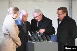 Премьер-министр Дании Метте Фредериксен, канцлер Германии Олаф Шольц, глава концерна Rheinmetall Армин Паппергер и министр обороны ФРГ Борис Писториус (слева направо) рассматривают образцы боеприпасов