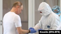 Владимир Путин (слева) во время посещения больницы для пациентов с коронавирусной инфекцией в Москве. Архивное фото