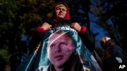 A woman holds a photo of her son, a Ukrainian officer, during a gathering in Kyiv in support of soldiers who defended Mariupol and are still in Russian captivity after 2 1/2 years.