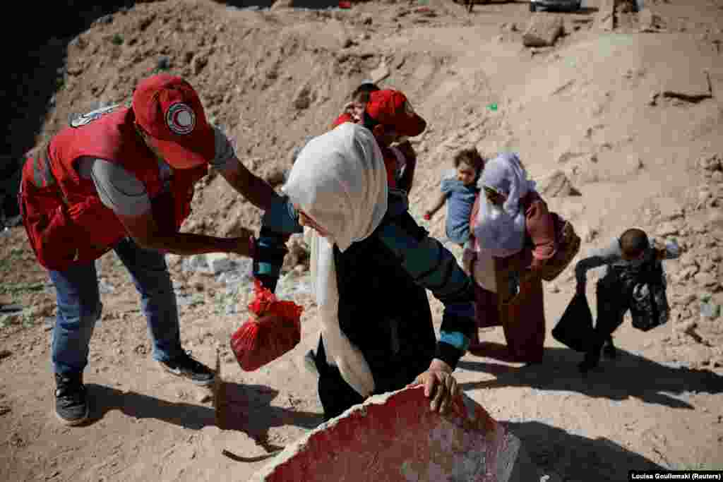 Punonjësit e Gjysmëhënës së Kuqe Arabe Siriane, duke i ndihmuar gratë dhe fëmijët në pikëkalimin kufitar Masnaa.