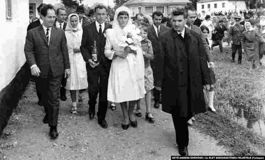 Nicolae Ceaușescu însoțește un cuplu maghiar proaspăt căsătorit, în apropiere de Brașov (1967).&nbsp; Deși Ceaușescu a supravegheat represiunea pe scară largă a oponenților săi politici, el a fost inițial popular în rândul românilor - mai ales după ce a luat împrumuturi străine, care asigurau aprovizionarea cu alimente a magazinelor din țară.