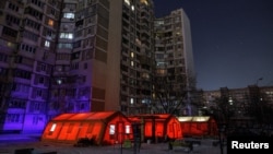 Палатки пункта гуманитарной помощи, где киевляне могут согреться, зарядить свои устройства, получить горячие напитки и психологическую поддержку, установлены рядом с многоквартирными домами после недавних российских ударов. Киев, 12 января 2026 года