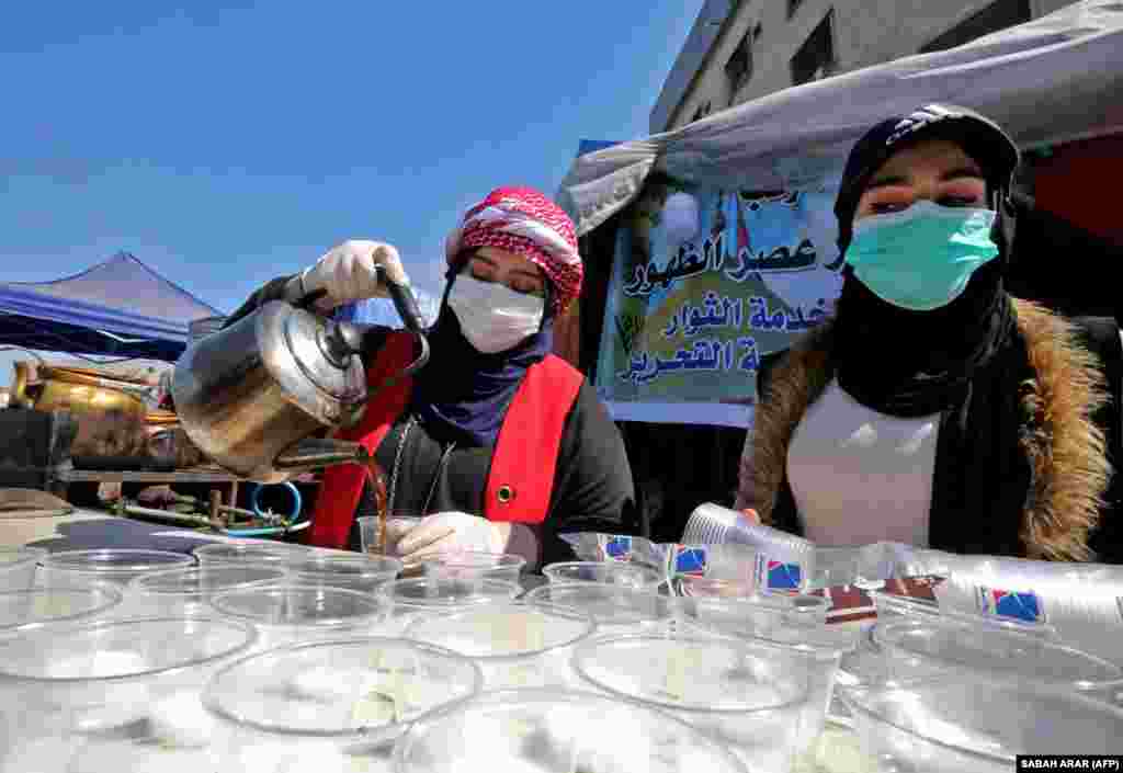 Иракские женщины в защитных масках подают чай на площади Тахрир в Багдаде, где антиправительственные демонстранты продолжают&nbsp;сидячую забастовку с октября прошлого года. На прошлой неделе власти Ирака сообщили о первом подтвержденном случае коронавируса - в священном городе Наджаф. Данная новость вызвала&nbsp;панику в стране, так как этот город является крупнейшим&nbsp;экспортным рынком&nbsp;и популярным направлением для иранских паломников - мусульман-шиитов. 4 марта 2020 года. 