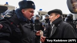 Russian human rights activist Lev Ponomaryov (right) speaks with a police officer during a rally in front of the FSB headquarters in central Moscow on March 14.