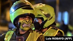 Police officers use face masks as a preventive measure against the spread of the new coronavirus, COVID-19, in Cali, Colombia on March 20, 2020.