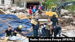 Rescue workers and locals in the village of Glogosnica begin cleaning up on October 5, a day after deadly floods and landslides in southern Bosnia. 