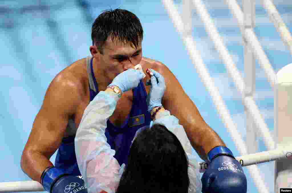Врач оказывает первую помощь казахстанскому боксеру. Но поскольку не удалось остановить кровь, судьи прекратили поединок