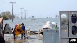 Pakistani victims affected by massive flooding in September sit with their belongings in Sindh province.