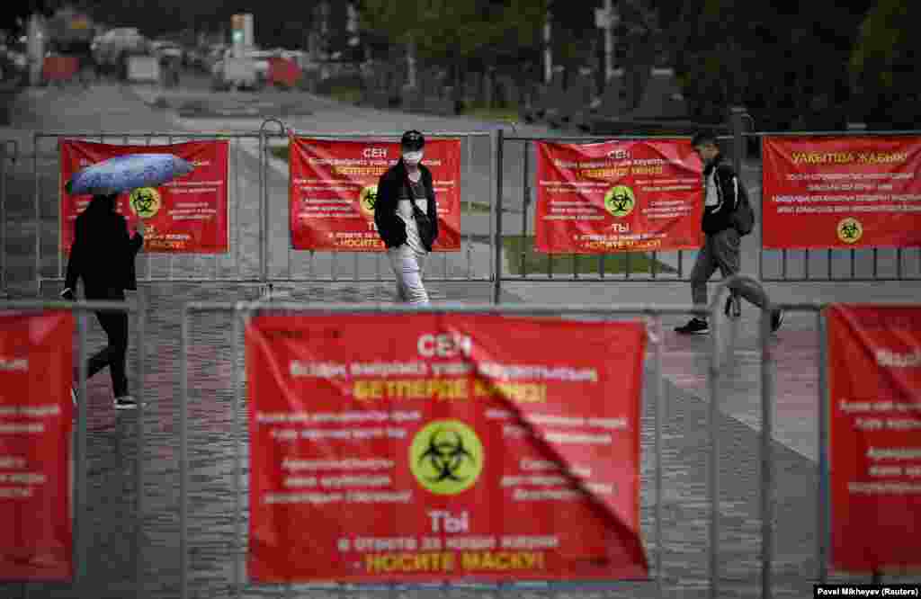 People walk past banners informing of preventive measures against COVID-19 in Almaty, Kazakhsta. (Reuters/Pavel Mikheyev)