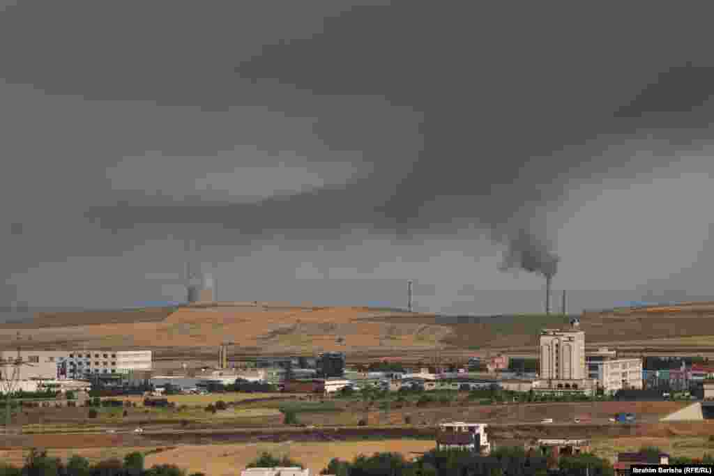 Tymi i dendur del nga termocentralet me thëngjill në Obiliq, me shtëpitë e Fushë Kosovës në sfond, duke theksuar problemet serioze të ndotjes së ajrit. Blloqet në termocentralin Kosova A janë ndër shkaktarët më të mëdhenj të ndotjes së ajrit në vend.