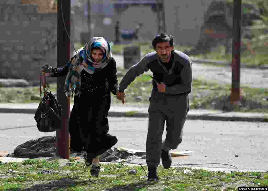 Civilians run for cover as they flee Mosul&#39;s Al-Tayaran neighborhood on February 28. According to Reuters, the first thing many civilians ask Iraqi forces for is a cigarette. Smoking was forbidden under Islamic State rule.&nbsp;