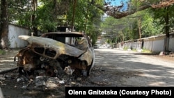 Випалена російським дроном цивільна автівка у Херсоні на тлі антидронових сіток