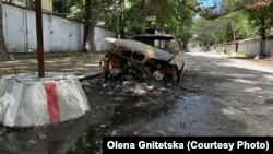 Випалена російським дроном цивільна автівка у Херсоні на тлі антидронових сіток (архівне фото)