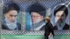 A woman in Tehran walks past a banner bearing the images of former Iranian supreme leaders Ayatollah Ruhollah Khomeini (left), Ayatollah Ali Khamenei (center), and his son, the current supreme leader, Mojtaba Khamenei. 