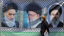 A woman in Tehran walks past a banner bearing the images of former Iranian supreme leaders Ayatollah Ruhollah Khomeini (left), Ayatollah Ali Khamenei (center), and his son, the current supreme leader, Mojtaba Khamenei. 