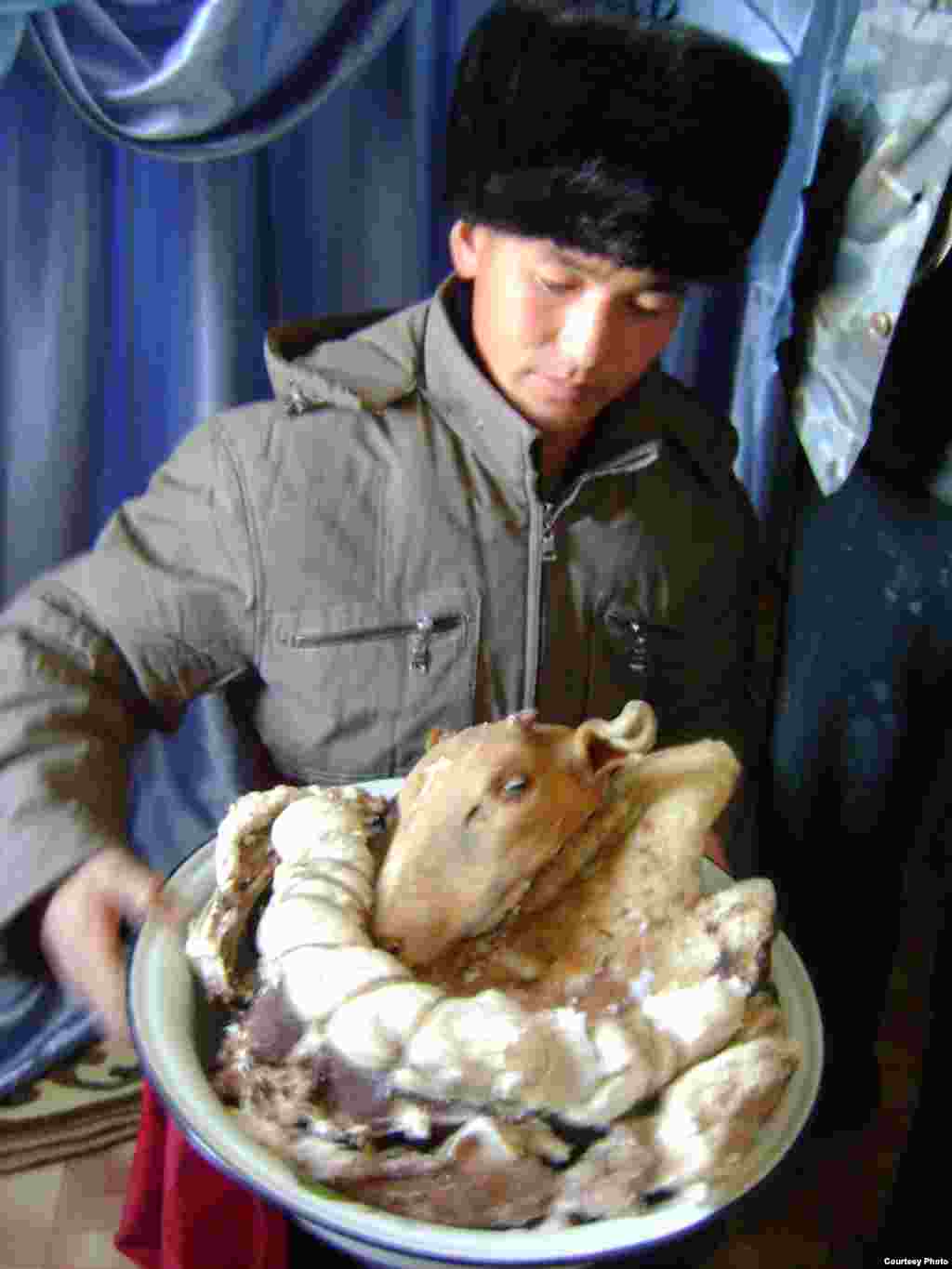 The groom holds a platter with a sheep&#39;s head and cuts of meat while guests say blessings for the couple.