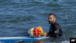 Un bărbat aduce un omagiu celor 3 surferi dispăruți în Ensenada, Mexic, duminică, 5 mai 2024.