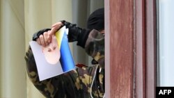 A pro-Russian activist rips a photo of interim President Oleksandr Turchynov as he stands at a window of the regional administration building in Luhansk.