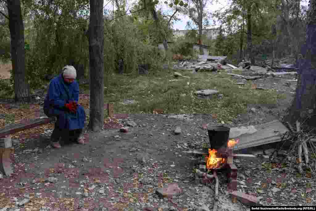 Жителька Костянтинівки Світлана гріє воду на відкритому вогні біля зруйнованих будинків. На запитання кореспондента Радіо Свобода про те, чи не страшно залишатися у місті, жінка відповідає: «Страшно, але в нас виходу немає»