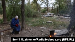 Жителька Костянтинівки Світлана підігріває воду біля зруйнованих будинків, 29 вересня 2025 року