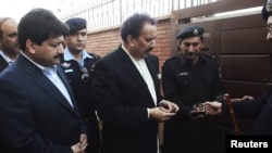 Senior journalist for the Geo News television station Hamid Mir (left) watches as police officers show a bomb found under his car to Interior Minister Rehman Malik (center) in Islamabad in November 2012.