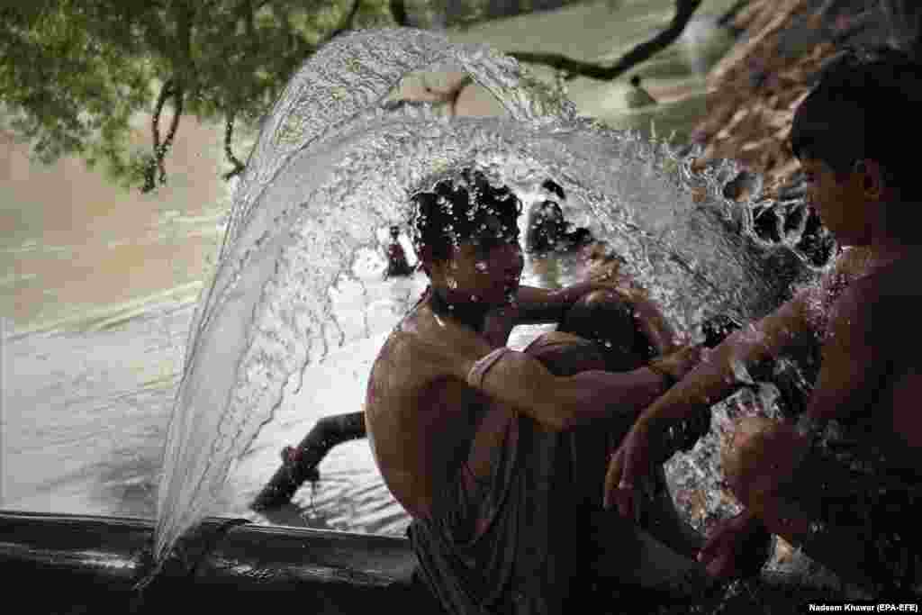 Пакистанские мальчики охлаждаются в канале, пока в Карачи продолжается жара