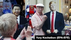 Un bărbat pozând cu imaginile lui Donald Trump și Xi Jinping la Moscova