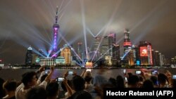 Зрители смотрят световое шоу на набережной Бунд в Шанхае, устроенное по случаю 100-летия основания Коммунистической партии Китая, 1 июля 2021 года
