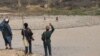 Afghan policemen wave at Taliban fighters in a remote frontline in the southern province of Uruzgan on February 25.