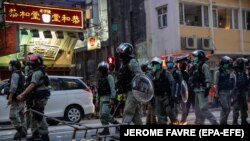 Policajci prolaze pored improvizirane barikade koju su zapalili demonstranti tokom skupa protiv zakona o nacionalnoj sigurnosti u Hong Kongu, Kina, 1. jula 2020.