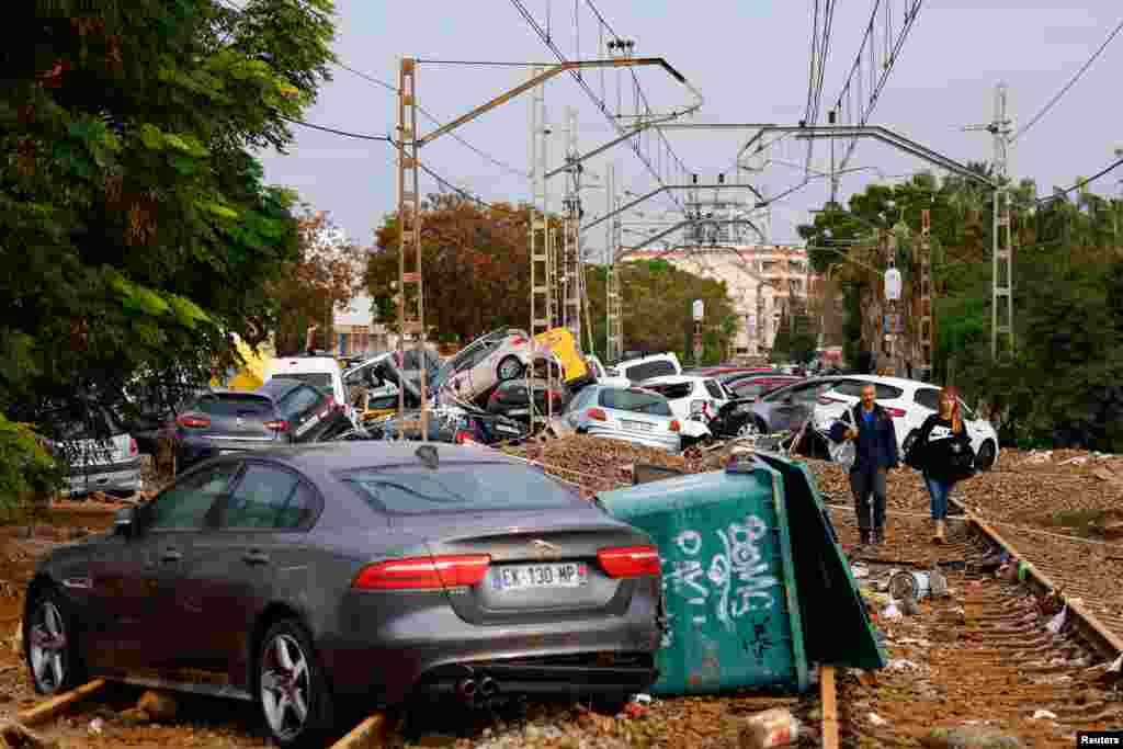 Ljudi prolaze pored automobila koje su na gomilu navukle velike poplave, Alfafar, 1. novembra 2024. Ova katastrofa najgora je u decenijama za Španiju, a vlasti upozoravaju stanovnike da hitna situacija još nije završena.