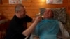 Vitaliy Shumey smiles and speaks to his father, Serhiy, who has been by his son's side since he was wounded in August 2022. The Ukrainian soldier has been recovering in the western city of Truskavets and has regained his ability to speak.