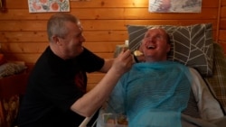 Vitaliy Shumey smiles and speaks to his father, Serhiy, who has been by his son's side since he was wounded in August 2022. The Ukrainian soldier has been recovering in the western city of Truskavets and has regained his ability to speak.