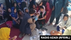 مردی در دایکندی دخترانی که گفته می‌شود مسموم شده‌اند را مدوا می‌کند