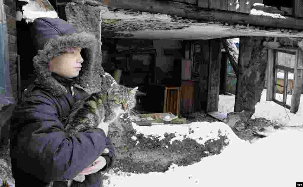 A boy holds a cat outside his home, which reportedly was damaged by shelling, in Donetsk, Ukraine. (epa/Alexander Ermochenko)