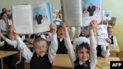 Belarus -- Pupils hold books about President Alyaksandr Lukashenka at a school in Minsk, September 1, 2012