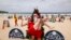 Tourists wearing Christmas costumes pose in front of a Christmas tree on the sand at Bondi Beach in Sydney on December 25, 2025. (Photo by DAVID GRAY / AFP)
