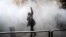 An Iranian woman raises her fist amid the smoke of tear gas at the University of Tehran during a protest driven by anger over economic problems in December 2017.