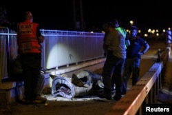 Israeli security and rescue personnel work next to a part of a projectile following a missile attack from Iran in northern Israel on June 8.