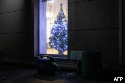 Generator electric în fața unei ferestre decorate cu pomul de crăciun la Odesa, pe 22 decembrie 2025.