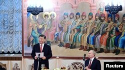 A kínai elnök beszédet mond orosz kollégája társaságában egy moszkvai fogadáson 2023. március 21-én