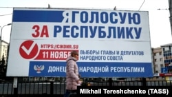 A woman walks past an election campaign billboard on a street in Donetsk on November 7.