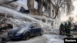Пожарникарите работат на местото на зградата што беше погодена од руски дрон, за време на рускиот напад врз Украина, во Киев, Украина, 12 јануари 2026 година.