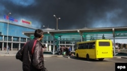 Ок атышуулардан улам күйүп жаткан Донецк аэрпортун карап турган киши. Донецк, 2-октябрь, 2014-жыл.