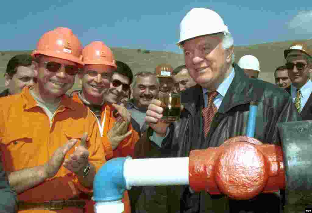 Georgian President Eduard Shevardnadze toasts with a glass of freshly extracted oil as he visits an oil field in Taribana near Tbilisi, during his 2000 election campaign.