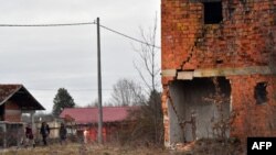 Migranti prolaze pored ruinirane kuće u mjestu Bosanska Bojna u blizini hrvatske granice (januar 2021.)