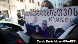 Жінка тримає плакат із зображенням ув'язненого лідера опозиції Ніки Мелії на мітингу на його підтримку перед будівлею парламенту в Тбілісі, Грузія, 02 березня 2021. Поліція взяла штурмом штаб-квартиру Об'єднаного національного руху (УНМ) і заарештувала голову партії Мелія 23 лютого 2021 року